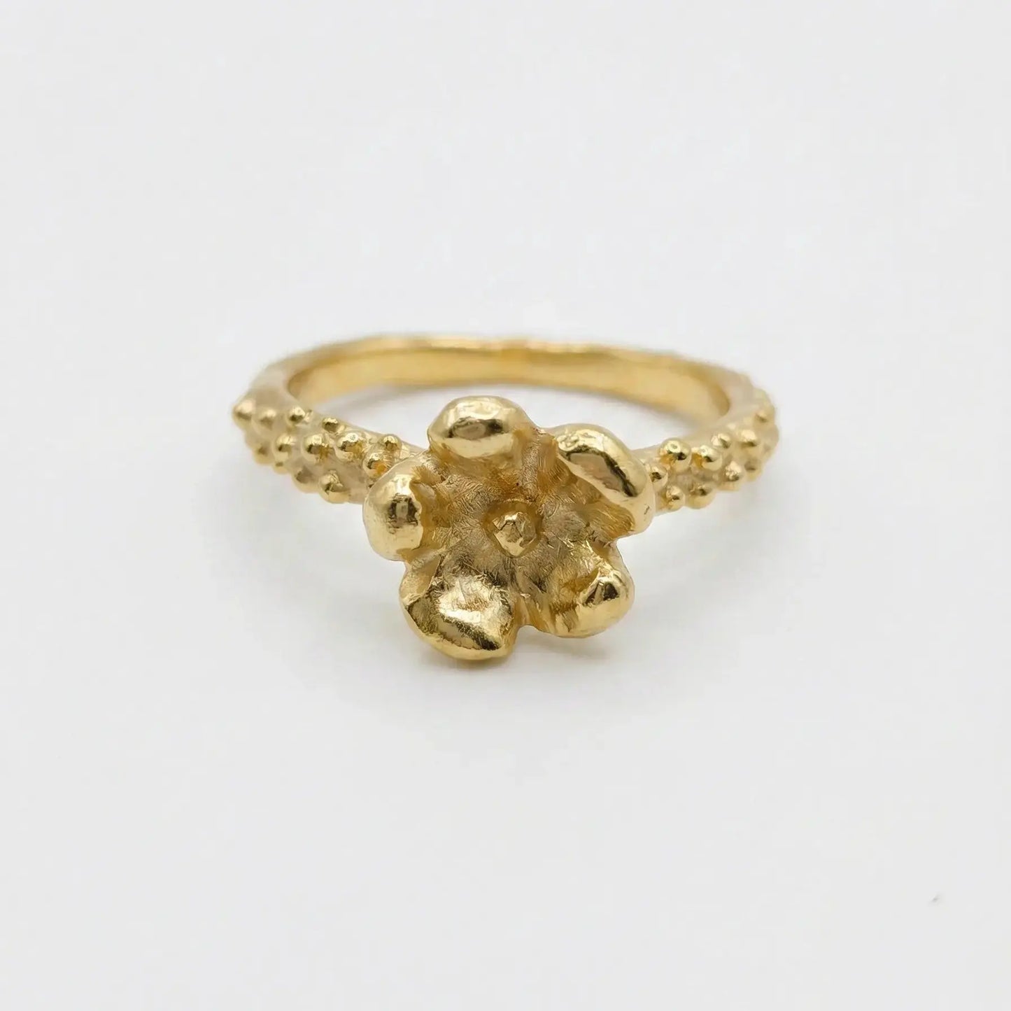 Anello floreale in bronzo dorato fatto a mano, castone a forma di fiore materico e gambo con granulazione artigianale, Made in Italy.