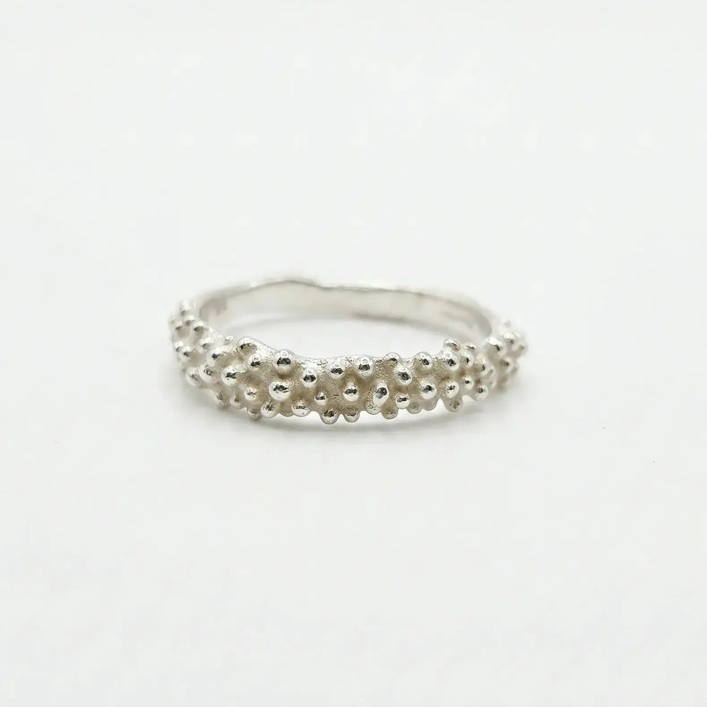 Anello artigianale in bronzo placcato argento con texture organica a granuli irregolari. Finitura semilucida, design unico ispirato alle forme naturali e marine, ideale per uno stile materico e contemporaneo