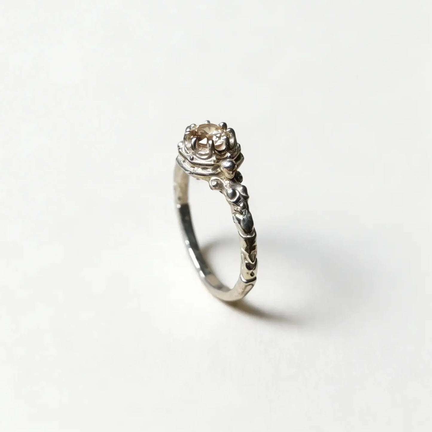 Anello solitario artigianale in argento, design botanico con castone decorato e finitura brunita, fatto a mano in Italia.