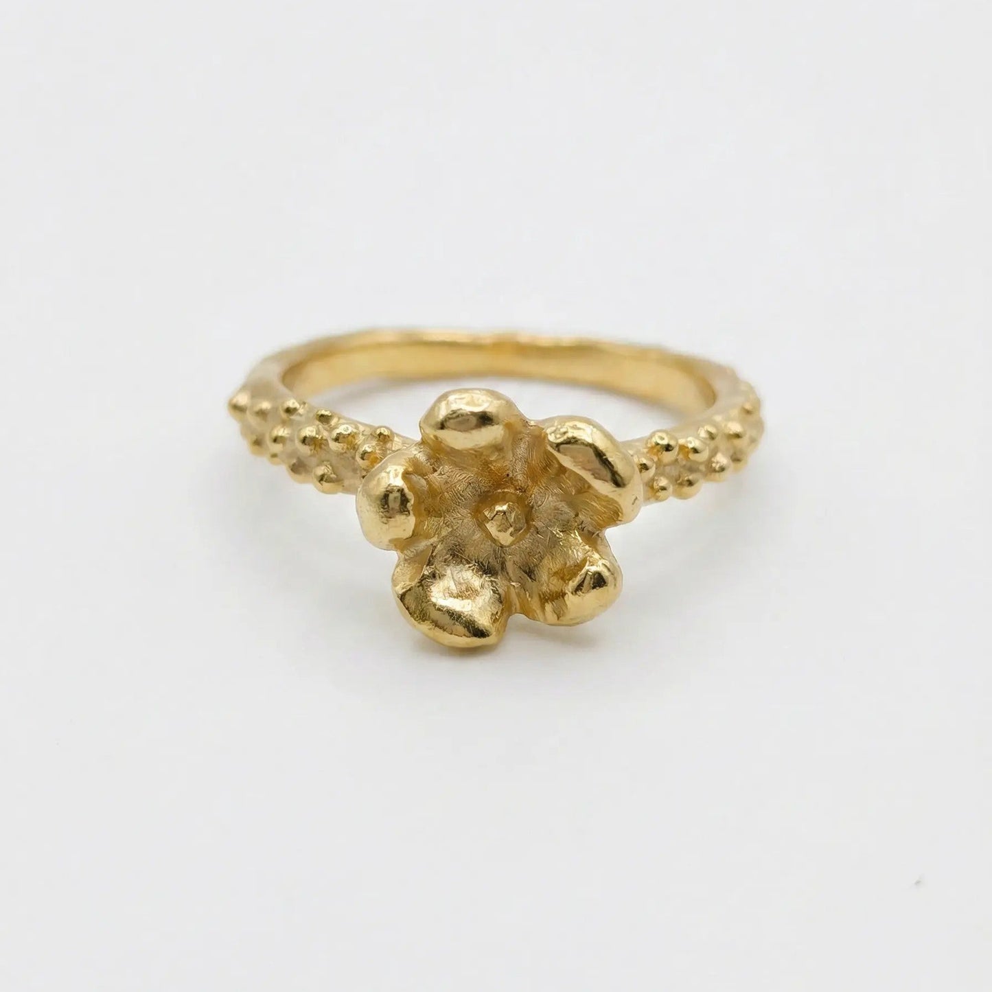 Anello floreale in bronzo dorato fatto a mano, castone a forma di fiore materico e gambo con granulazione artigianale, Made in Italy.