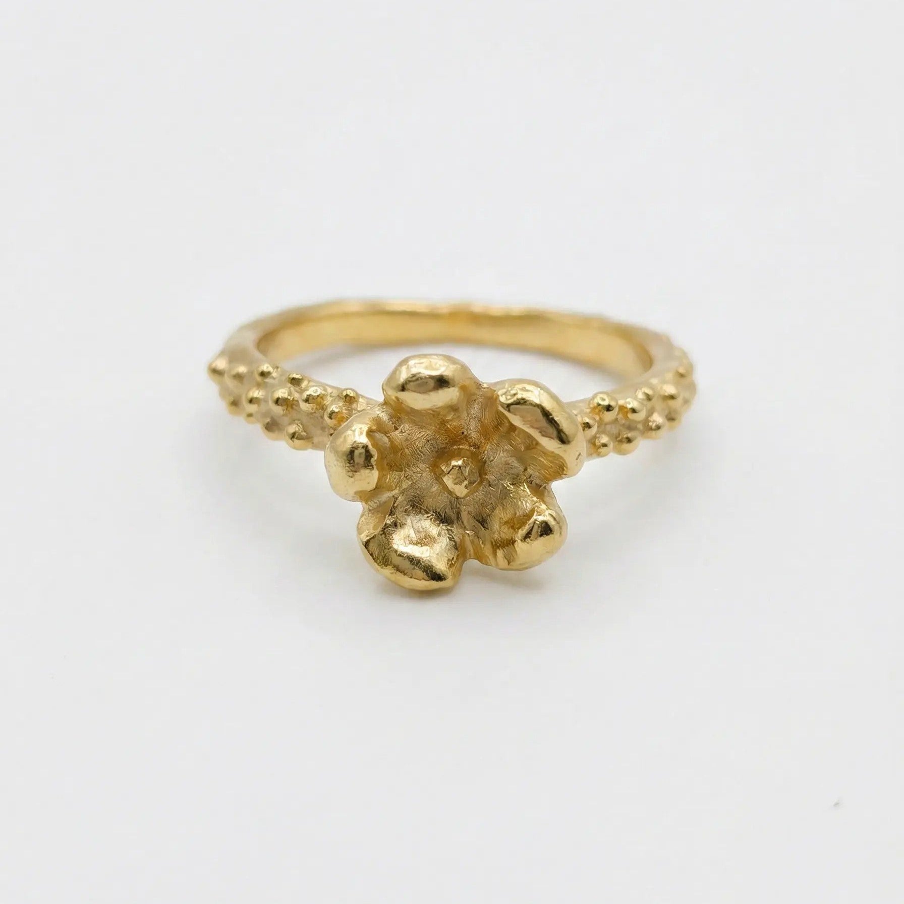 Anello floreale in bronzo dorato fatto a mano, castone a forma di fiore materico e gambo con granulazione artigianale, Made in Italy.