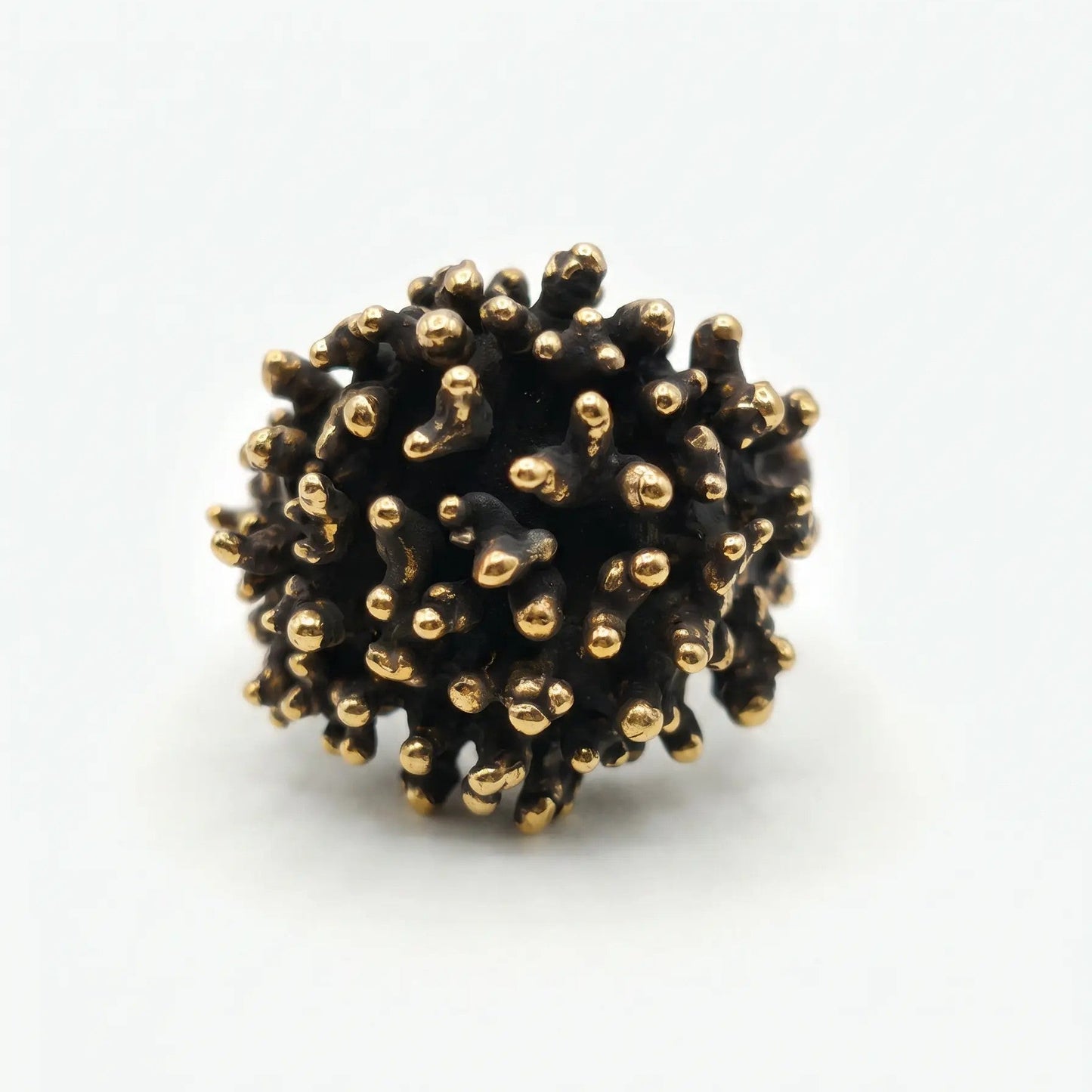 Anello scultura in metallo bicolore con finitura brunita e punte lucide, design ispirato alla natura marina o corallo, vista frontale dell'intera struttura e del gambo.