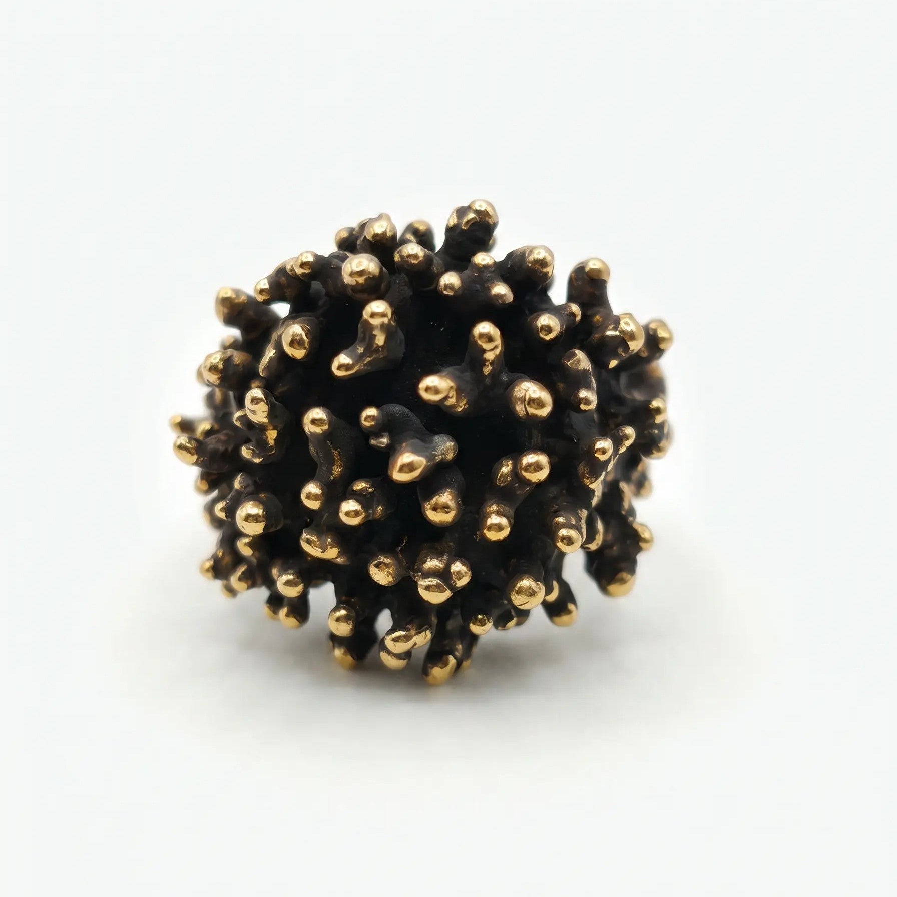 Anello scultura in metallo bicolore con finitura brunita e punte lucide, design ispirato alla natura marina o corallo, vista frontale dell'intera struttura e del gambo.
