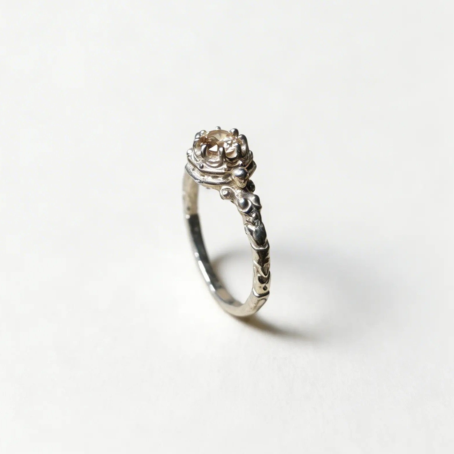 Anello solitario artigianale in argento, design botanico con castone decorato e finitura brunita, fatto a mano in Italia.
