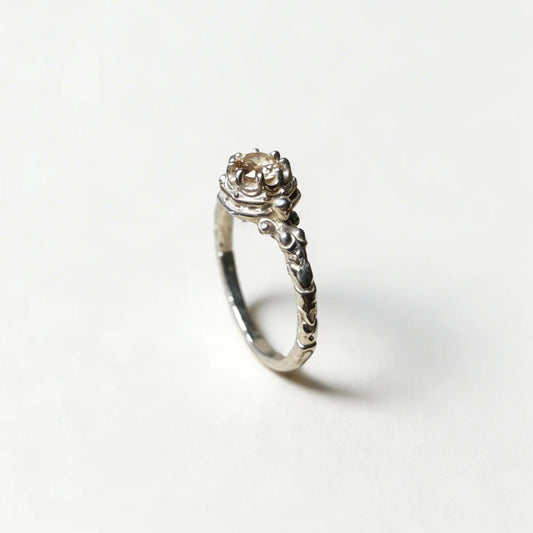 Anello solitario artigianale in argento, design botanico con castone decorato e finitura brunita, fatto a mano in Italia.
