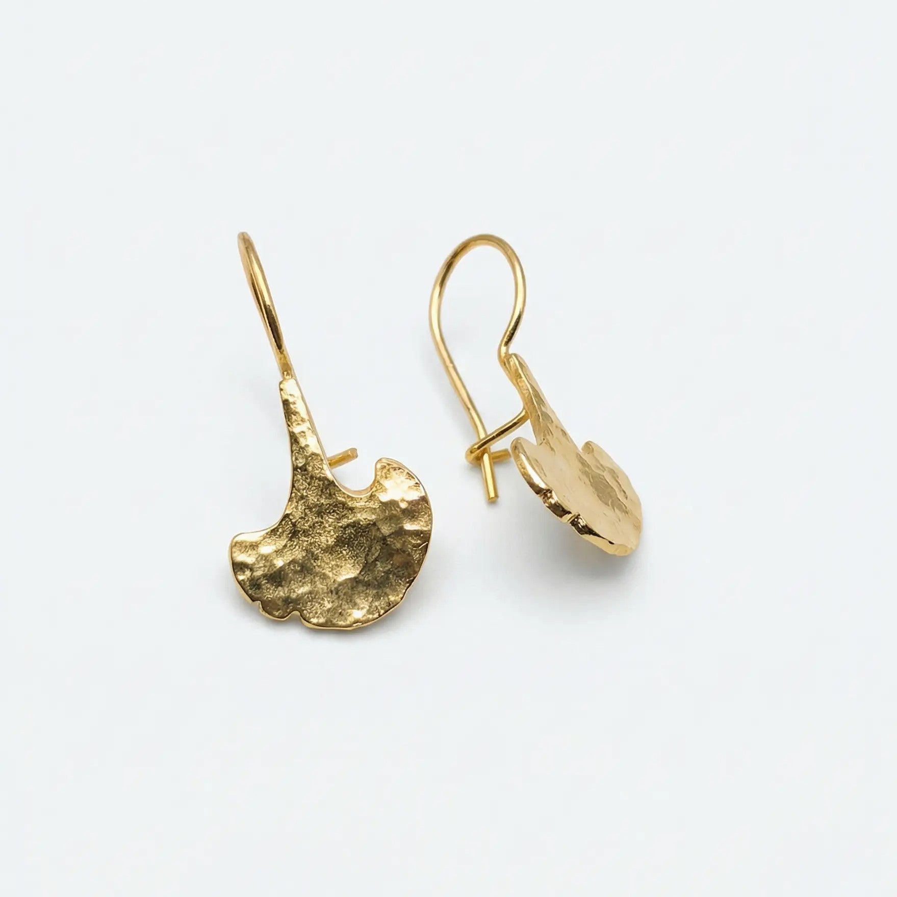 Orecchini handmade in bronzo bagnato oro, forma ginko biloba, vista studio su sfondo bianco retro 